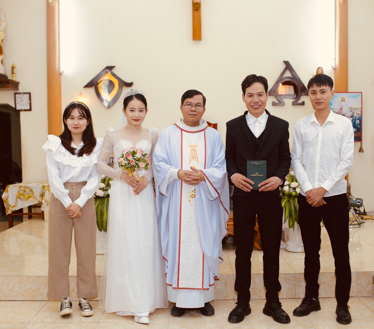 Cô dâu, chú rể chụp ảnh cùng bạn bè và cha xứ sau Thánh lễ