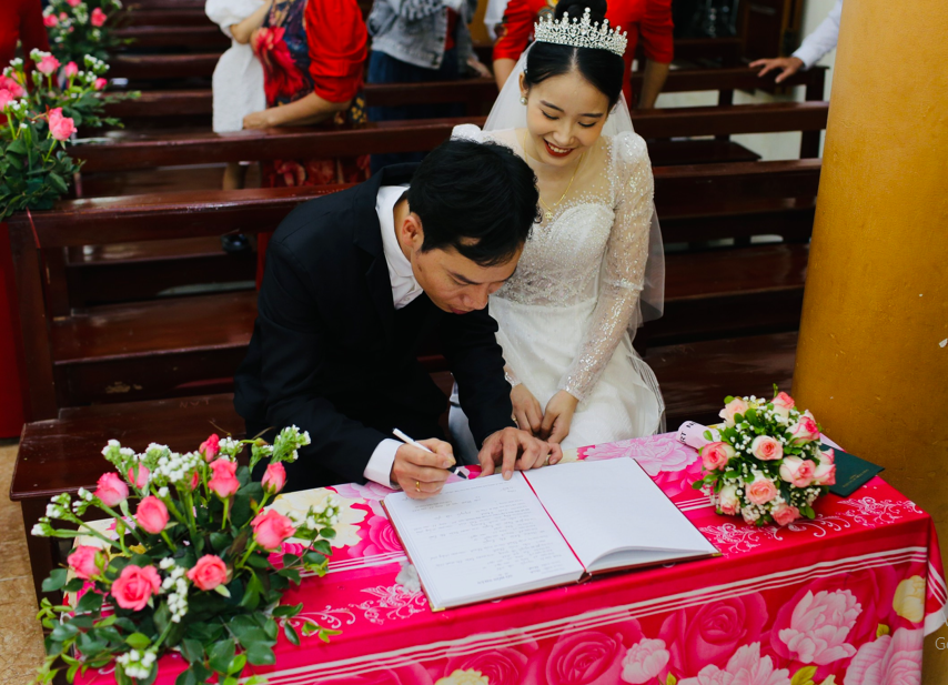 Cô dâu chú rể lần lượt ký vào sổ hôn phối